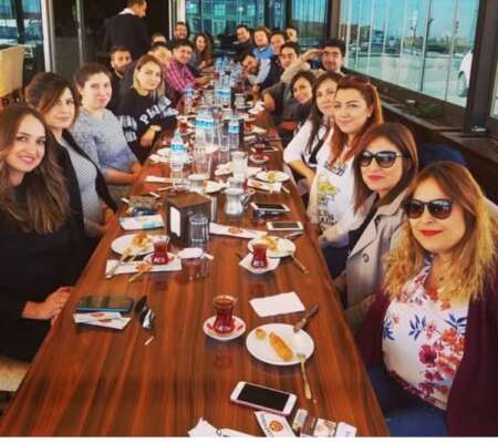 Yavuz Usta Oltu Cağ Kebabı restoranında, uzun bir masada bir grup insan masada tatlı ve çay eşliğinde fotoğraf çekiniyor.